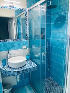 ein blau gefliestes Bad mit einem Waschbecken und einer Dusche in der Unterkunft Apartaments B&M in Ischia
