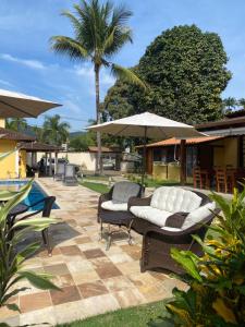 a patio with two lounge chairs and an umbrella at Pousada Antígona in Paraty