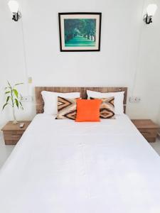 um quarto com uma cama branca e uma almofada laranja em Lavender em Le Morne