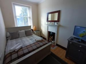 a bedroom with a bed and a tv and a fireplace at The Granary in The Square in Grantown on Spey