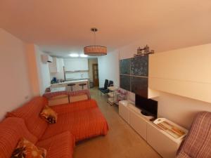 a living room with an orange couch and a kitchen at APARTAMENTO EL TIMON in Carboneras