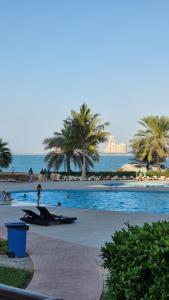 a swimming pool with palm trees and the ocean at Full Sea view studio in Ras al Khaimah