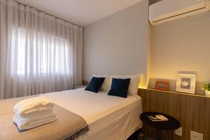 1 dormitorio con 1 cama con sábanas blancas y almohadas azules en Avenue Studio - GRU, en Guarulhos