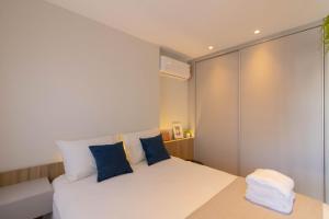 1 dormitorio con cama blanca y almohadas azules en Avenue Studio - GRU, en Guarulhos