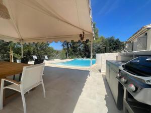 a patio with a table and a grill and a pool at La villa des Carriers- maison avec piscine proche mer in Roquefort-les-Pins