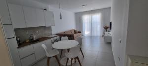 eine weiße Küche mit einem Tisch und Stühlen im Zimmer in der Unterkunft Toni Apartment in Sarandë