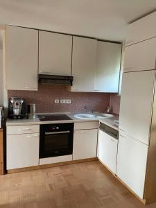 EberndorfにあるFerienwohnung Schimunの白いキャビネットと黒い食器洗い機付きのキッチンが備わります。