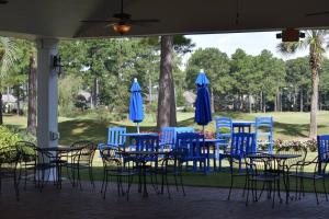 an outdoor patio with blue chairs and tables and umbrellas at Brunswick Plantation Resort and Golf Villas 2302L in the Heart of NC Seafood Country studio in Calabash