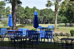 a group of tables with blue chairs and umbrellas at Brunswick Plantation Resort and Golf Villas 2302L in the Heart of NC Seafood Country studio in Calabash