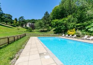 a swimming pool with chairs and a fence at The Retreat in Blackawton