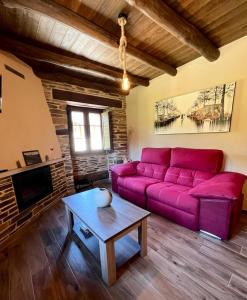 sala de estar con sofá púrpura y mesa en Casa A Poza, en Samos