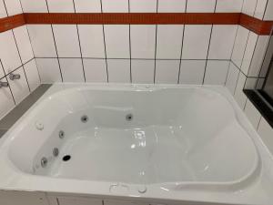 e bagno con vasca bianca e piastrelle bianche. di Motel Jaguar Contagem a Contagem Altre 32 foto