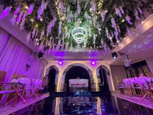 a wedding hall with purple flowers and tables at Kaya Hotel Amman in Amman