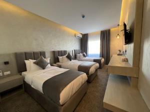 um quarto de hotel com duas camas e uma televisão em Kaya Hotel Amman em Amã