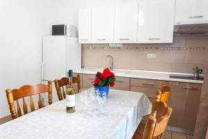 een keuken met een tafel met wijnglazen en rode bloemen bij Apartments & Room Diana in Pakoštane