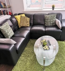 1 sofá de cuero negro con mesa de cristal en la sala de estar en J Quarter - sleeps 5 long term & families comfortably, 4 beds, 2 bathrooms, en Birmingham