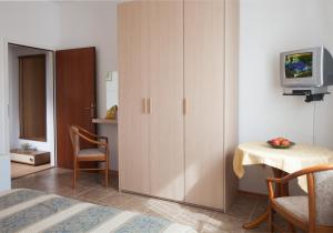 a bedroom with a cabinet and a table and a television at B&B Moderno in Fažana