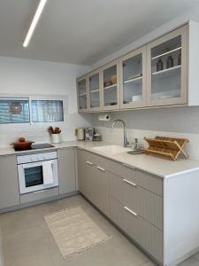 uma cozinha com armários cinzentos e um lavatório em BOHO and BE em Qiryat Shemona