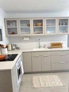 uma cozinha com armários brancos e um lavatório em BOHO and BE em Qiryat Shemona