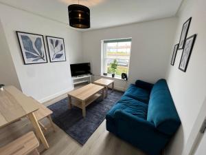 a living room with a blue couch and a table at Littlehampton House - 4 bedroom house sleeps 8 in Littlehampton