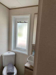 a bathroom with a sink and a toilet and a window at Ellis Retreats at Tattershall Lakes in Lincoln