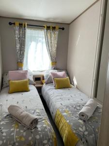 two beds in a small room with a window at Ellis Retreats at Tattershall Lakes in Lincoln