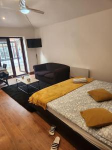 a bedroom with two beds and a couch and a chair at Cosy Studio Flat in Bexleyheath