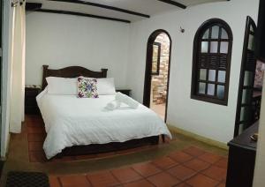 1 dormitorio con 1 cama con sábanas blancas y ventana en PUEBLITO BOYACENSE Hotel Boutique, en Duitama