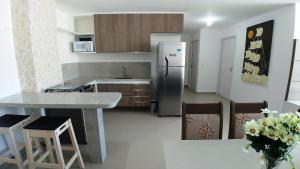 a kitchen with a refrigerator and a table and chairs at Areias do Mar ! 2 Quartos Familia com Varanda A213 in Barra de São Miguel