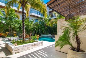 a swimming pool with palm trees and a building at 2 bedroom apartment at Aldea Zama by Casago in Tulum