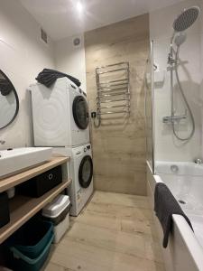 a bathroom with a shower and a washing machine at Soborna Apartment in Rivne