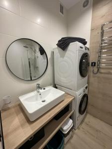 a bathroom with a sink and a washing machine at Soborna Apartment in Rivne