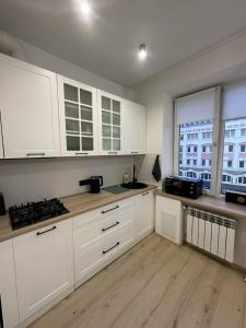 a kitchen with white cabinets and a wooden floor at Soborna Apartment in Rivne