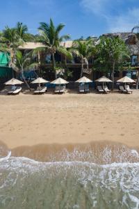 una playa con sillas y sombrillas. en Casa Bagus en San Agustinillo