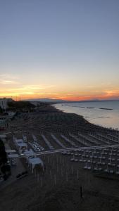 a beach with white umbrellas and the ocean at sunset at Residenza Belvedere in Termoli