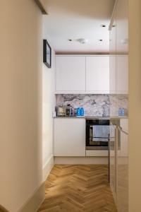a kitchen with white cabinets and a wooden floor at The Notting Hill Apartments By Hok Living - Nh1 in London
