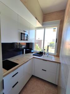 a kitchen with white cabinets and a sink and a window at Luminoso Apartamento enfrente del AVE in Puertollano
