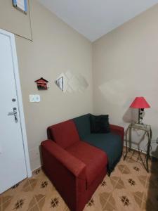 a living room with a red couch and a lamp at Apartamento em São Lourenço-mg in São Lourenço