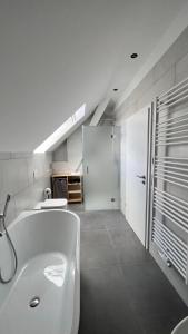uma casa de banho branca com uma banheira e um lavatório em New Nomads Ferienwohnung am See em Zossen
