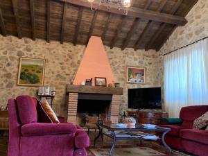 sala de estar con 2 sillas moradas y chimenea en Casa Rural "EL CONCEJO" en Aldehuela de la Bóveda