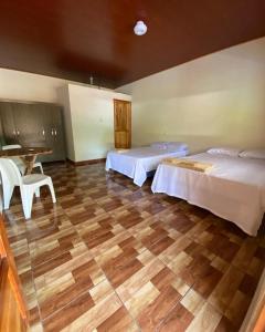 1 dormitorio con 2 camas y suelo de madera en Hostal las 3 J en Suchitoto