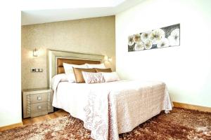 um quarto com uma cama grande com lençóis brancos e almofadas em Chalet Miranda. VV-1595-AS em Avilés