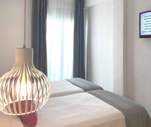 a bedroom with a bed with a lamp on it at Hotel Apartamentos Solimar in Calafell