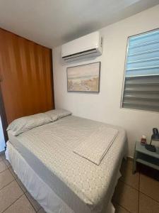 a bedroom with a bed and a air conditioner at Beach Front Apartments Seven Seas in Fajardo