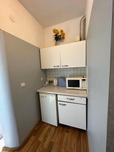 a small kitchen with white cabinets and a microwave at Radi in Brocēni