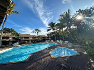 uma grande piscina com um deque de madeira e palmeiras em Aconchegante Casa Buzios em Búzios