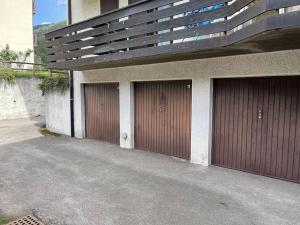3 garages avec portes brunes sur le côté d'un bâtiment dans l'établissement [Dolomiti] Paradiso in montagna nel verde + Sauna, à Carisolo