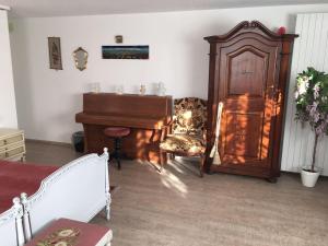 a living room with a piano and a chair at Double room in nice house near the forest (basement floor) in Brügg