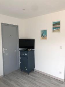 ein Zimmer mit einer Tür, einem Fernseher und einem Schreibtisch in der Unterkunft La maison bleue in Barneville-Carteret