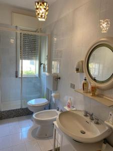 W łazience znajduje się umywalka, toaleta i lustro. w obiekcie A... Mare Sicilia w mieście Marina di Modica
